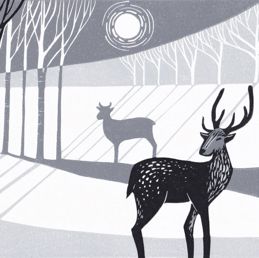 A lino print featuring two stylized deer in a woodland setting with moonlight.