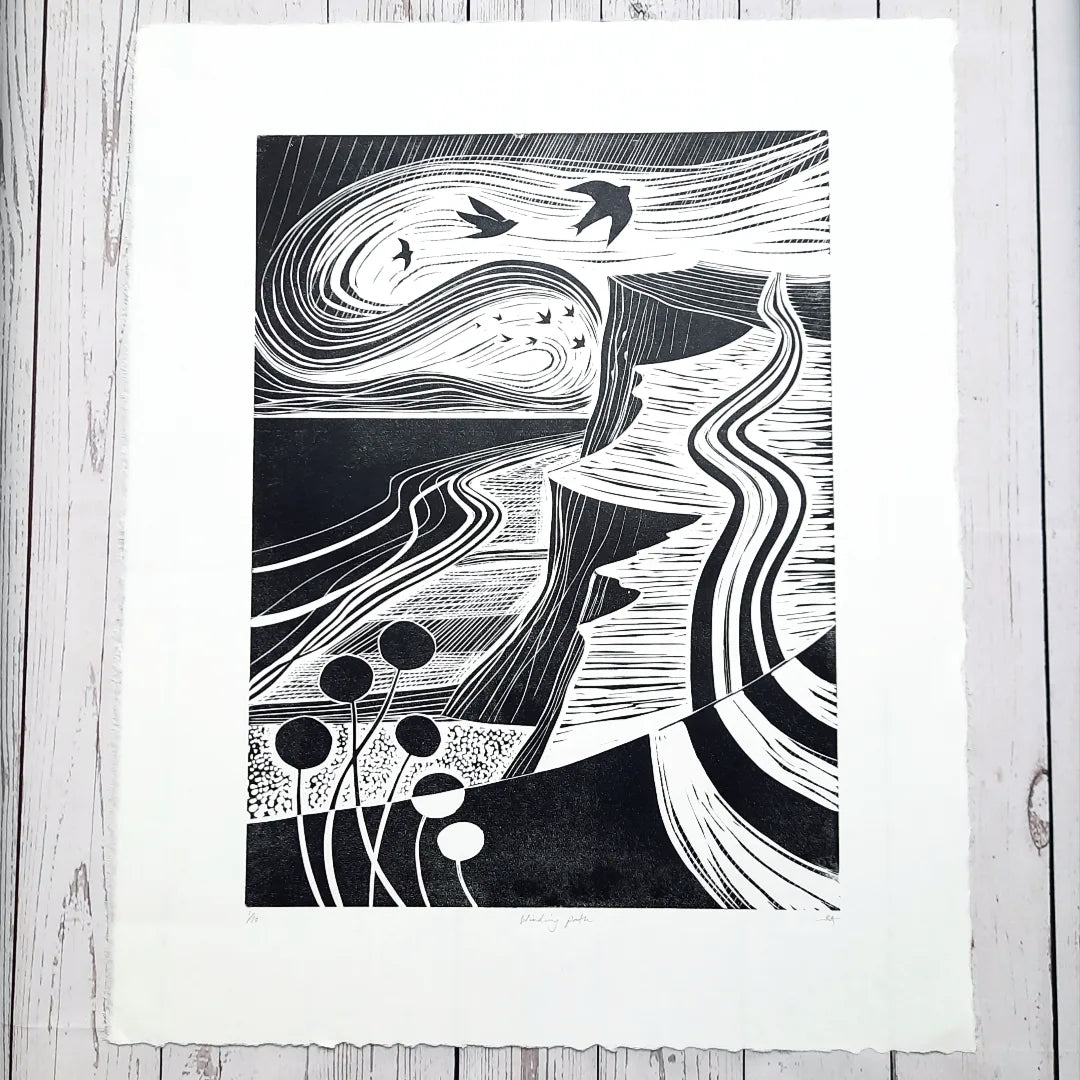 An original black and white lino print featuring a Norfolk coast path scene with birds and floral elements.