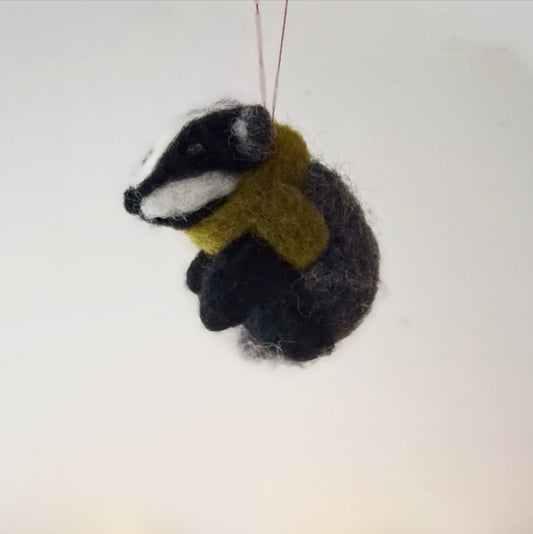 Felted badger ornament wearing a scarf on a white background