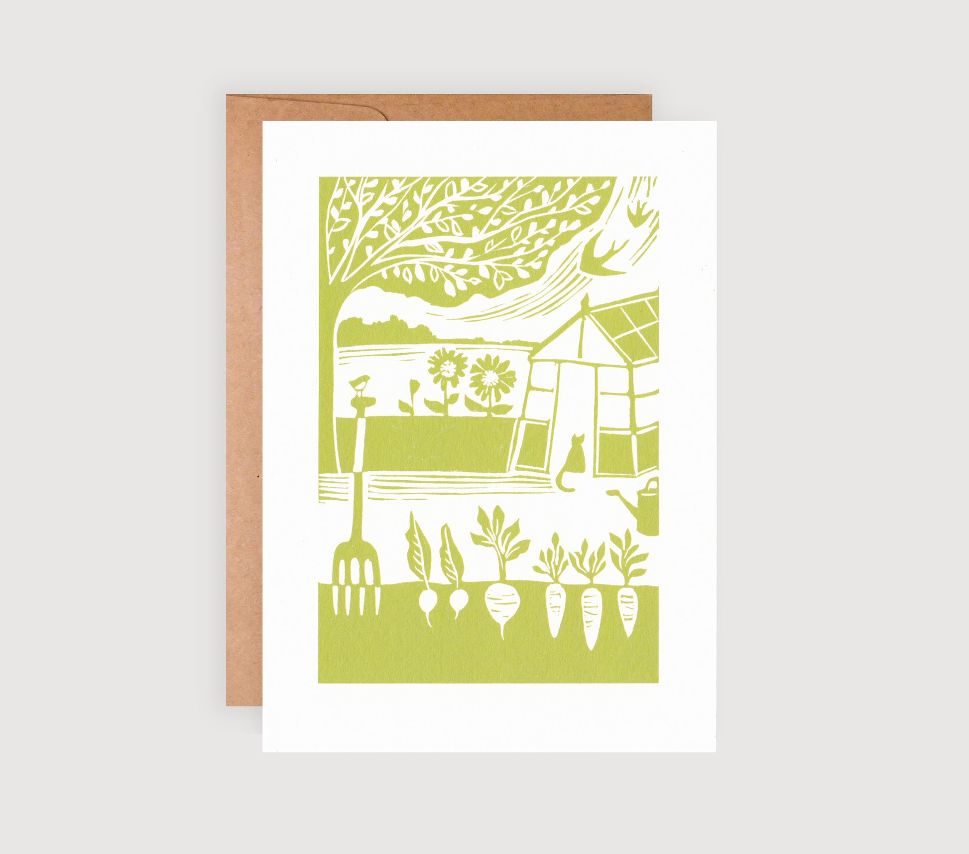 A greetings card with a green linocut print of a garden and a greenhouse, accompanied by a brown kraft envelope.