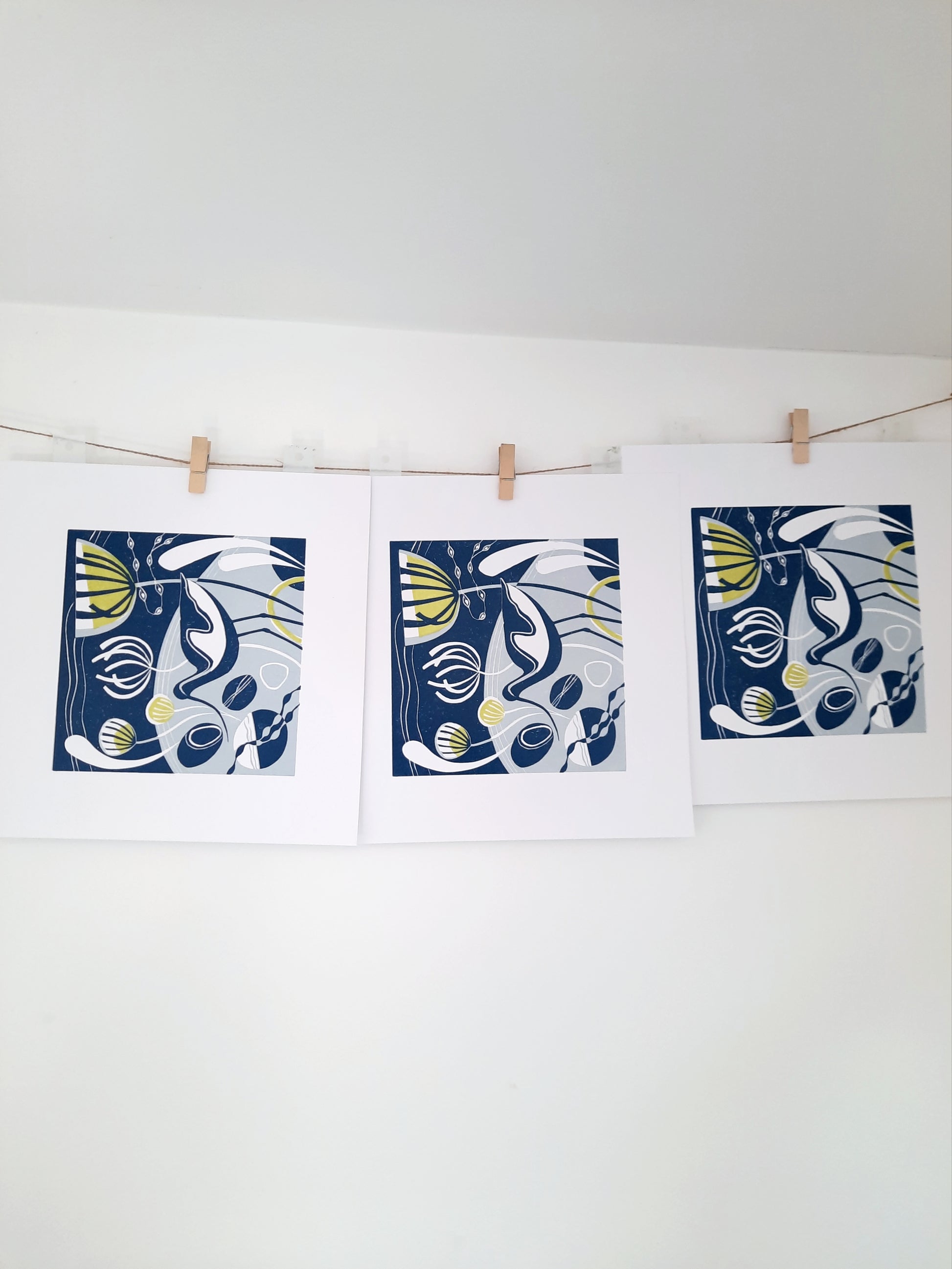Three unframed original lino prints featuring an avocet and stylised foliage, displayed on a wall.